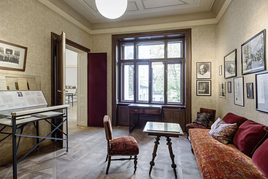 The waiting room of Sigmund Freud’s office in Vienna, Austria with a single chair facing a velvet couch and framed pictures on the wall.